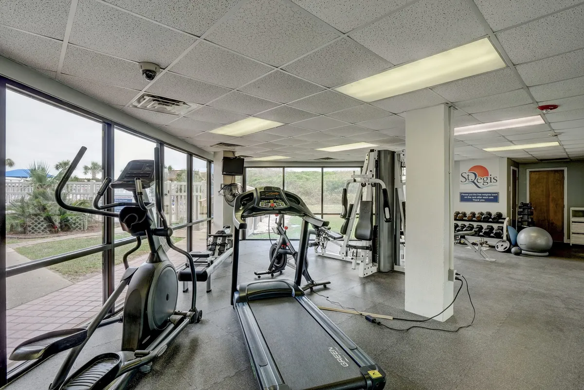 A bright, modern fitness center featuring treadmills, elliptical machines, weight training equipment, and floor-to-ceiling windows providing natural light and an energizing atmosphere.