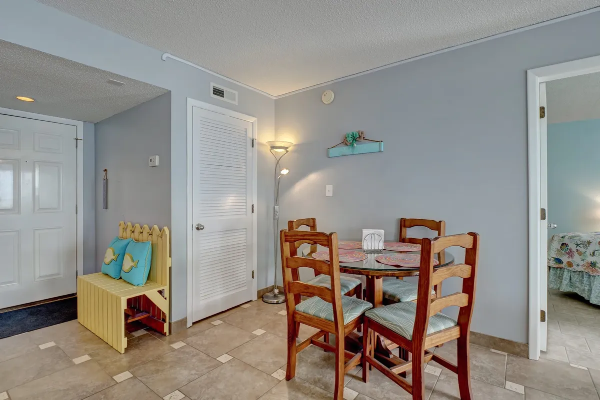 A welcoming dining area featuring a large table surrounded by comfortable seating, with decorative touches and an adjacent entryway. The setup is ideal for shared meals, festive gatherings, or cozy evenings spent in conversation.