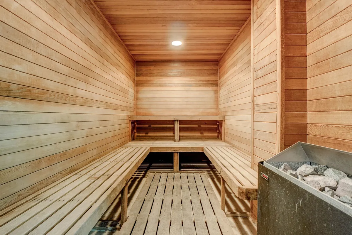 A tranquil sauna with wooden benches, soft lighting, and a classic stone heater invites quiet relaxation and rejuvenation after a workout or swim.